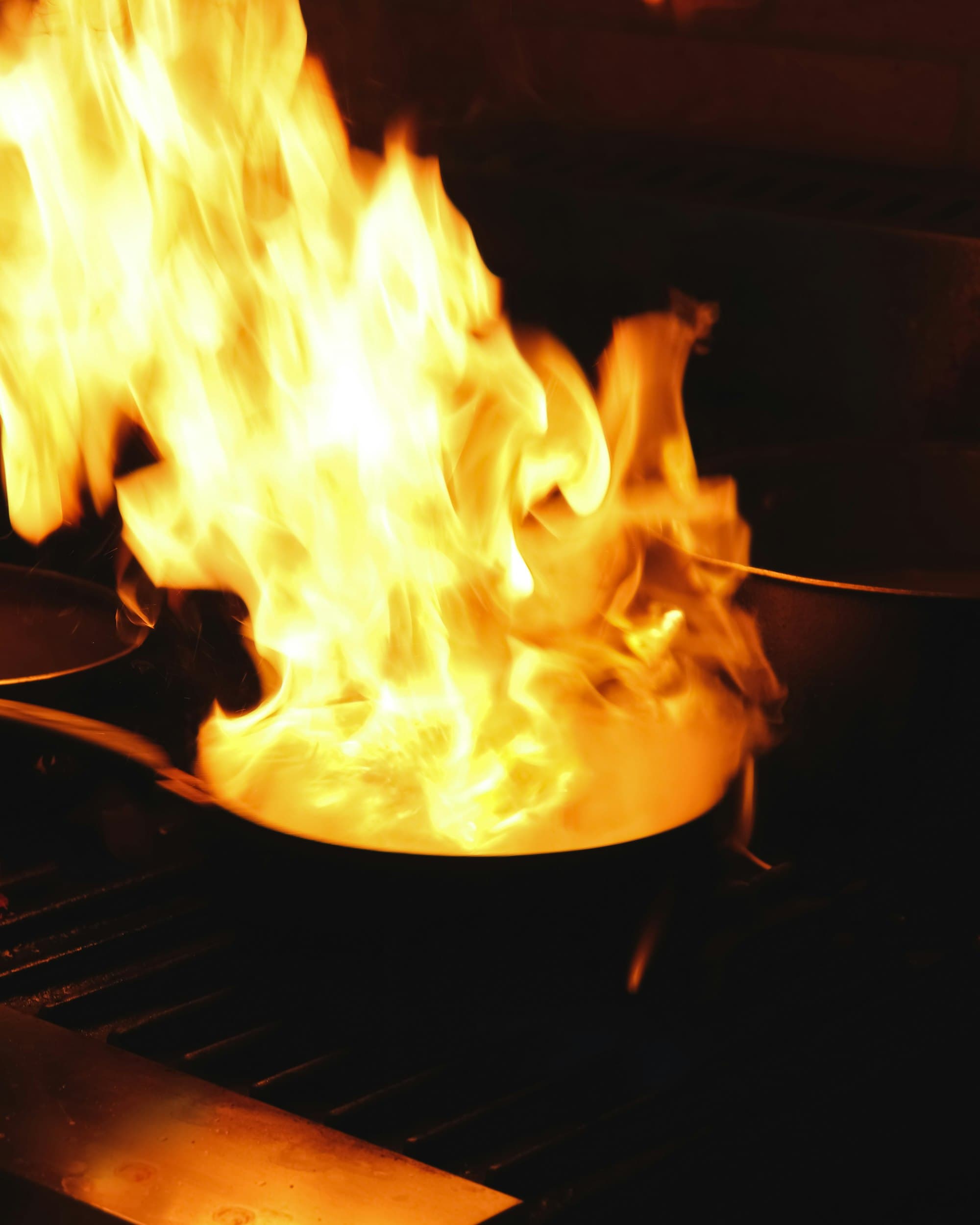 Flames erupting from a pan on an industrial restaurant stove