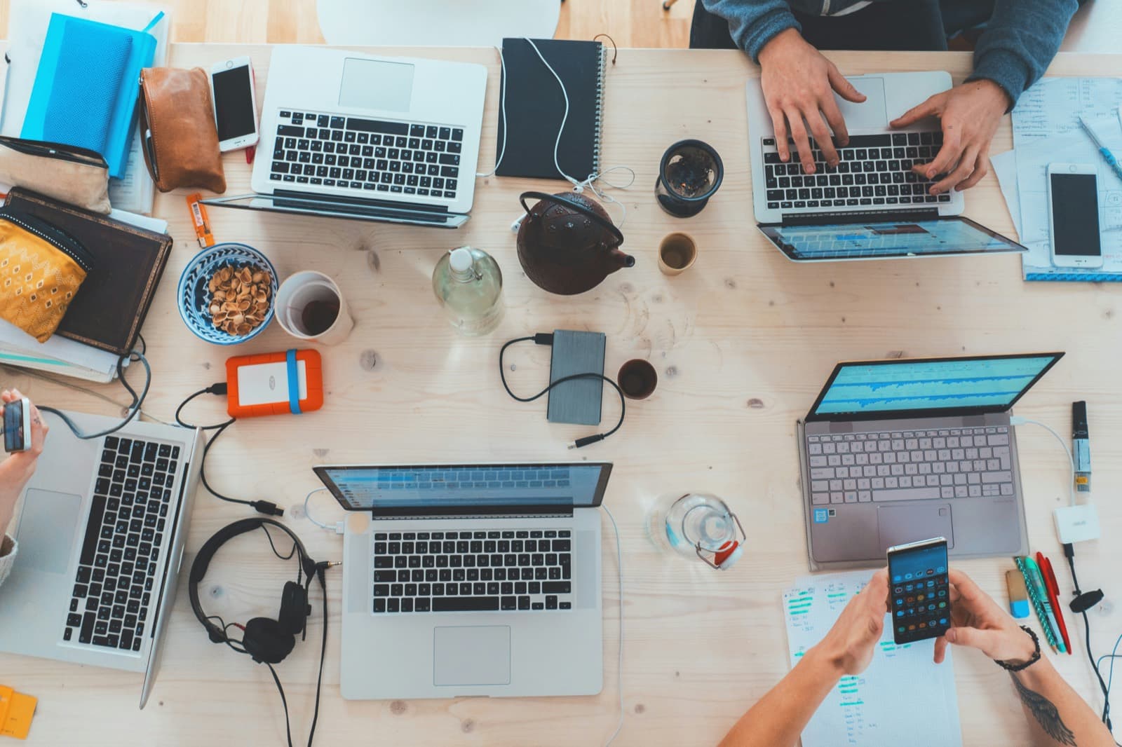 A small team sharing one table — laptops, notes, and tea